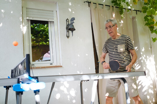 Senior man playing ping pong in home patio