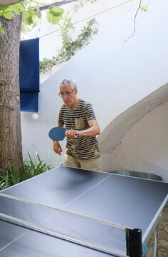 Senior man playing ping pong in home patio