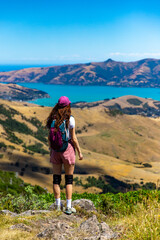 hiker girl admires the panorama of akaroa harbour and banks peninsula from the otepatotu scenic reserve, canterbury, new zealand south island near christchurch