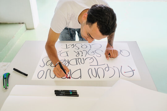 Gay man writes protest phrases in Spanish on a poster board