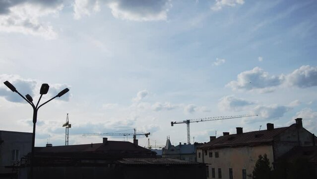 A serene daytime sky with towering construction cranes marking progress and change.