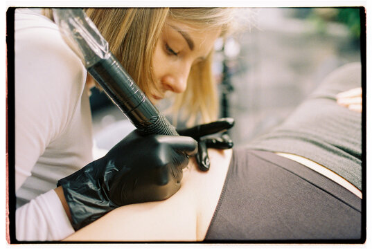 A woman tattoo artist making tattoo 