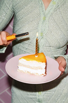 Crop woman lighting candle on piece of birthday cake