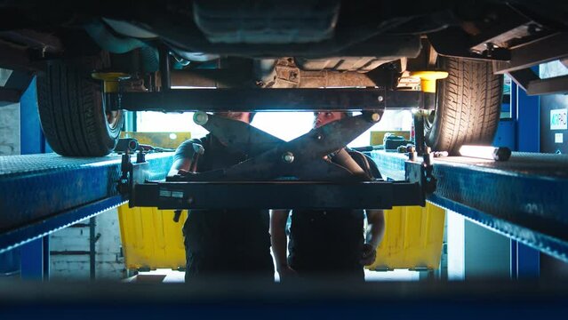 Two cheerful mechanics converse during a repair job, exuding camaraderie in a bright auto shop setting.