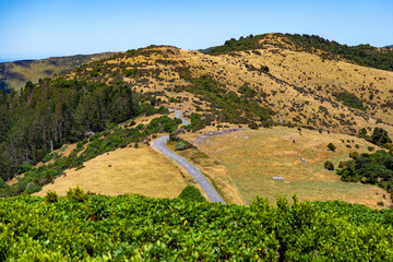 panorama of banks peninsula with winding road on a hill near akaroa harbour; canterbury, new...