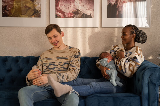 Man massaging feet of woman breastfeeding baby