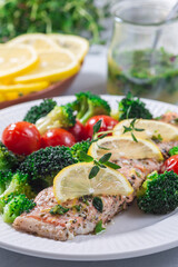Fototapeta na wymiar Salmon steak with vegetables, baked salmon fillet with broccoli and tomato on plate, vertical