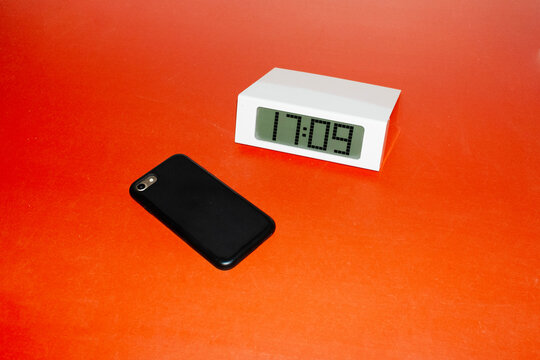 Contemporary photo of office table with smartphone and digital clock