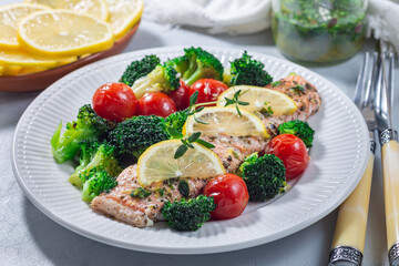 Baked salmon fillet with broccoli and tomato on plate, salmon steak with vegetables, horizontal