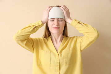 Young woman with brain concussion and bandaged head on beige background