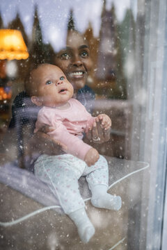 Happy mother shows falling snow to her baby