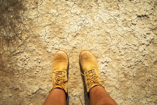 ugc of woman's feet with boots stepping on an arid and desert terrain