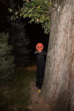Woman wearing pumpkin mask pulling hand toward camera