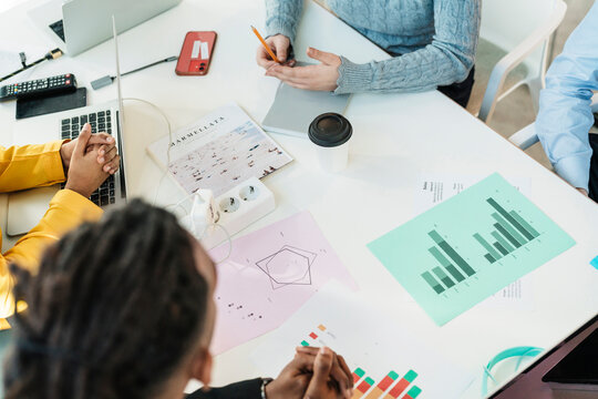 Colleagues discussing charts on table at workplace
