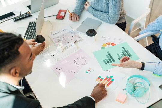 Colleagues discussing charts on table at workplace