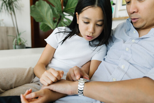 Daughter and father discussing the time on a wrist watch