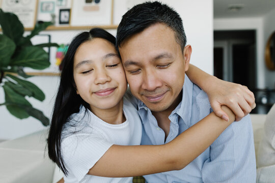 A girl with father cuddling on the sofa