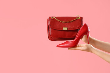 Female hands with stylish women's bag and high heels on pink background