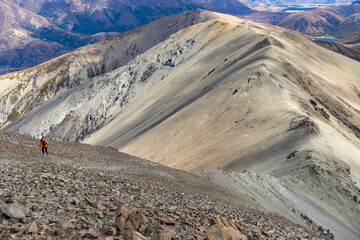 hiker girl walking down the steep and narrow rocky trail from castle hill peak in southern alps,...