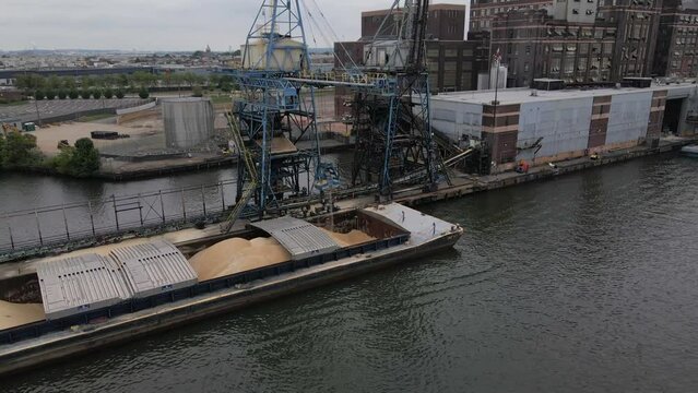 BALTIMORE - 1.19.2024 - Excellent aerial footage pulling away from a crane drawing sugar from a ship's hold to a waterfront refinery in Baltimore, Maryland.