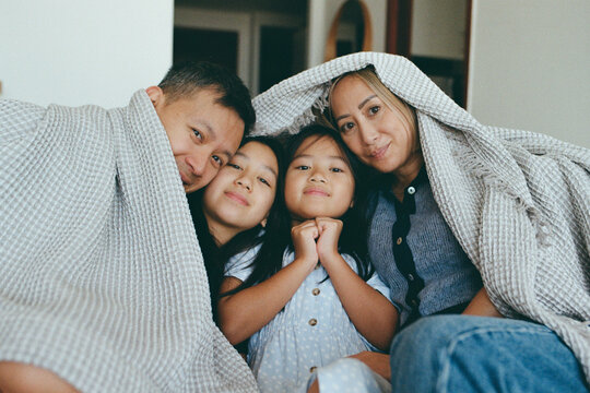Family of four at home under the blanket