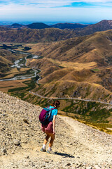 hiker girl walking on a rocky path between porters pass and foggy peak in torlesse tussocklands...