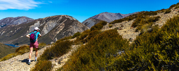 hiker girl walking on a rocky path between porters pass and foggy peak in torlesse tussocklands...