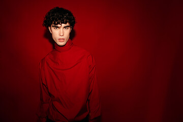 Stylish young man standing in pose against maroon wall