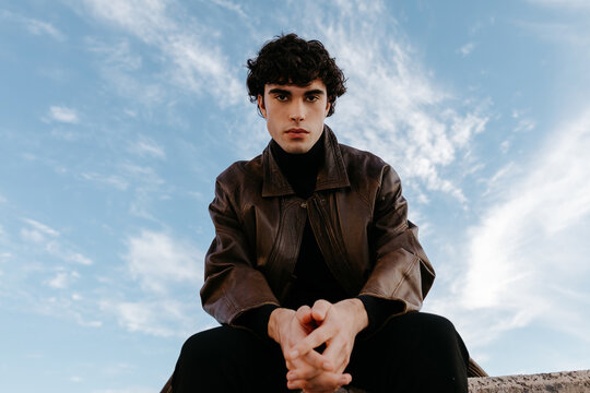 Stylish young man looking at camera against blue sky