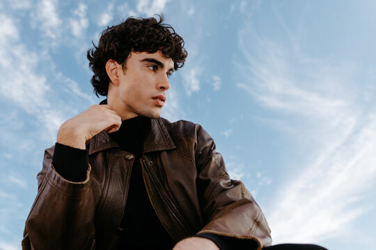 Thoughtful young man in warm jacket against blue sky