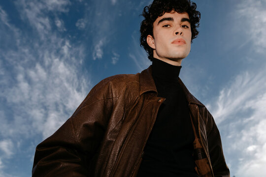 Stylish young man against blue sky with black high neck sweater