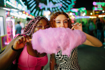 Two young girls having cotton candy at a fair