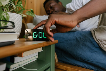 A man switching off his alarm clock