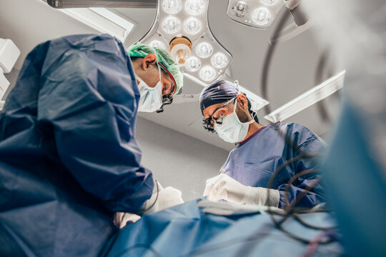Male doctors performing thyroid surgery in operating room