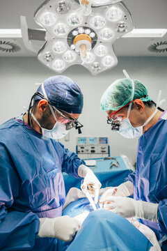 Male doctors performing thyroid surgery in operating room