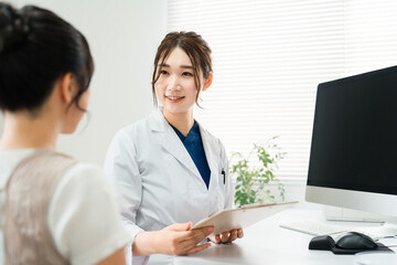 医師の診察を受ける女性・美容外科のカウンセリング・診療・問診・相談
