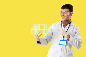 Male chemist with test tubes on yellow background