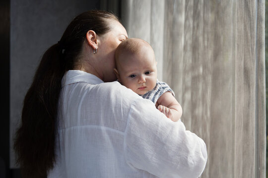 Woman with baby in her arms near the window