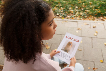 Black female sitting on bench with lost dog placard