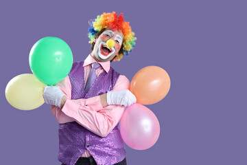 Fototapeta premium Portrait of clown with balloons on lilac background. April Fool's day celebration