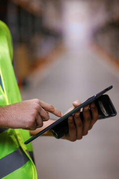 Anonymous storage worker using tablet scanner warehouse aisle