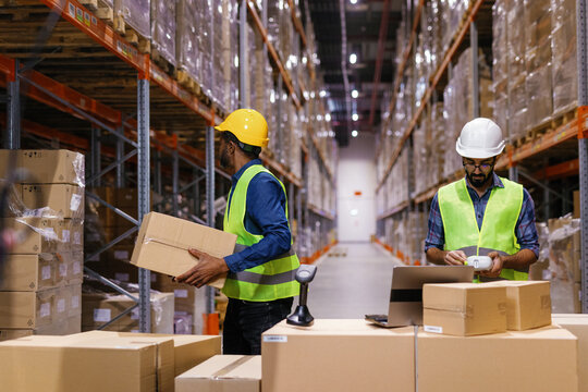 Two warehouse workers inventory boxes