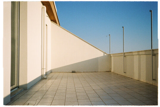 Empty terrace on a sunny morning: glass door, a shadow and blue sky