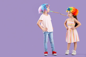 Little brother and sister with colorful wigs and party whistles on lilac background. April Fool's Day celebration