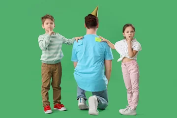 Behang Little kids sticking paper stickers to their father's back on green background. April Fool's Day celebration © Pixel-Shot