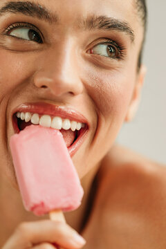 Portrait of young woman in studio eating ice cream 