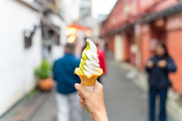Asian woman hand holding soft serve cone ice cream during travel at Asakusa district, Tokyo, Japan....