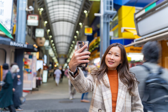 Happy Asian woman using mobile phone taking selfie during travel Sensoji Temple at Asakusa district, Tokyo, Japan. Attractive girl enjoy urban outdoor lifestyle travel city street on holiday vacation.