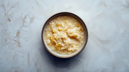 A minimalist image of chicken and pumpkin puree rice porridge for a baby food recipe, against a softly textured, clean background