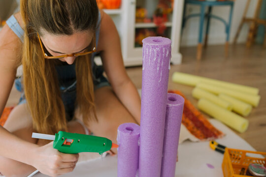 A woman using a glue gun for making a Halloween DIY